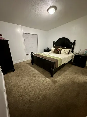 Carpeted bedroom featuring a textured ceiling and baseboards