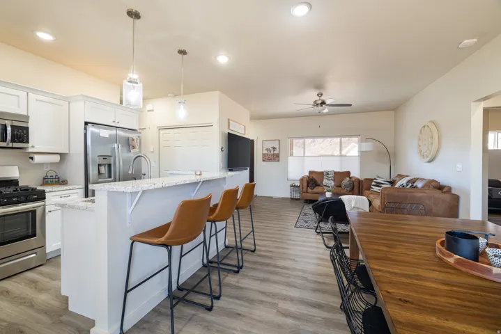 Kitchen featuring appliances with stainless steel finishes, ceiling fan, white cabinets, a kitchen breakfast bar, and decorative light fixtures