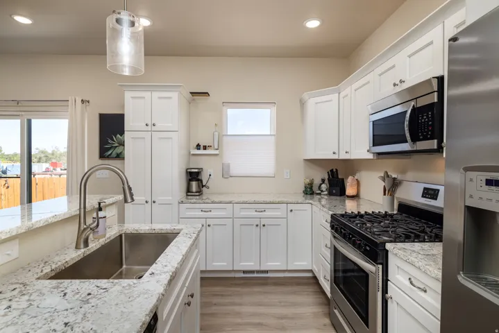 Kitchen featuring appliances with stainless steel finishes, white cabinets, decorative light fixtures, light wood-style floors, and recessed lighting