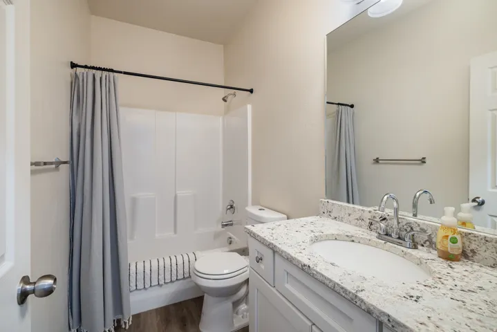 Bathroom with shower / bath combination with curtain, vanity, and dark wood-type flooring