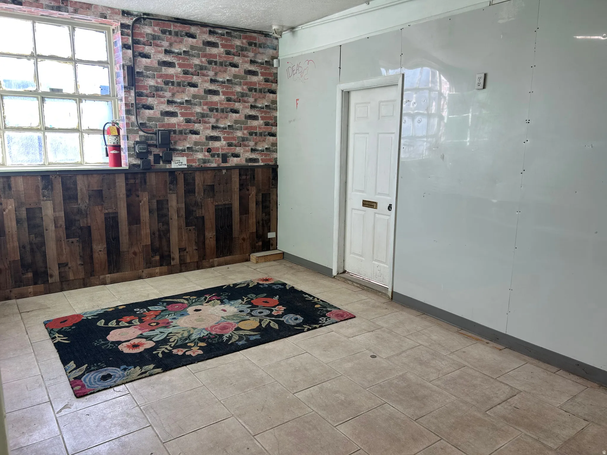 Entryway with wood walls, a wainscoted wall, a textured ceiling, and brick wall