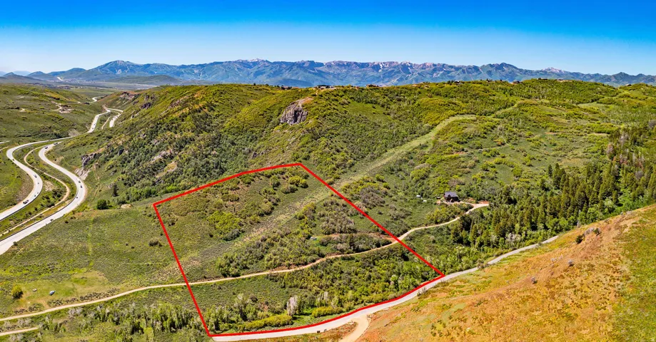 Aerial view of property and surrounding area with property boundaries highlighted and a mountain backdrop