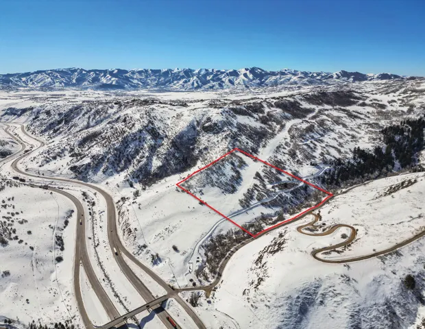 Snowy aerial view featuring property parcel outlined and a mountain view
