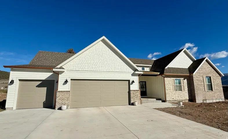 View of front facade with concrete driveway, an attached garage, and a shingled roof