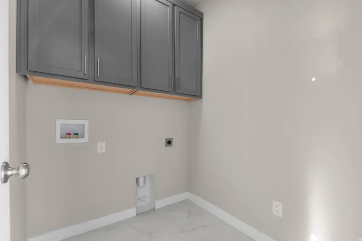 Laundry room featuring light marble finish floors, electric dryer hookup, hookup for a washing machine, and cabinet space