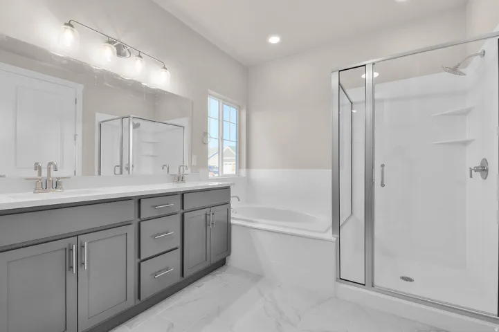 Bathroom featuring double vanity, a garden tub, a shower stall, light marble finish floors, and recessed lighting