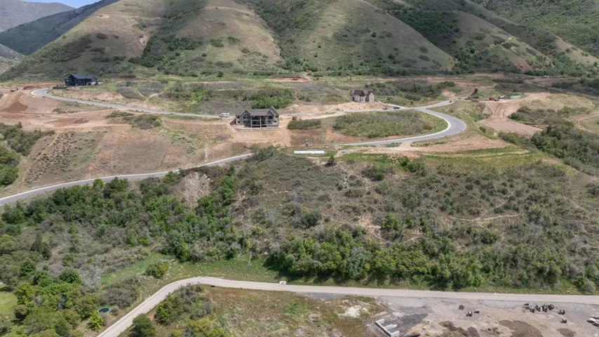 Expansive mountainous terrain with multiple graded building sites and paved roads