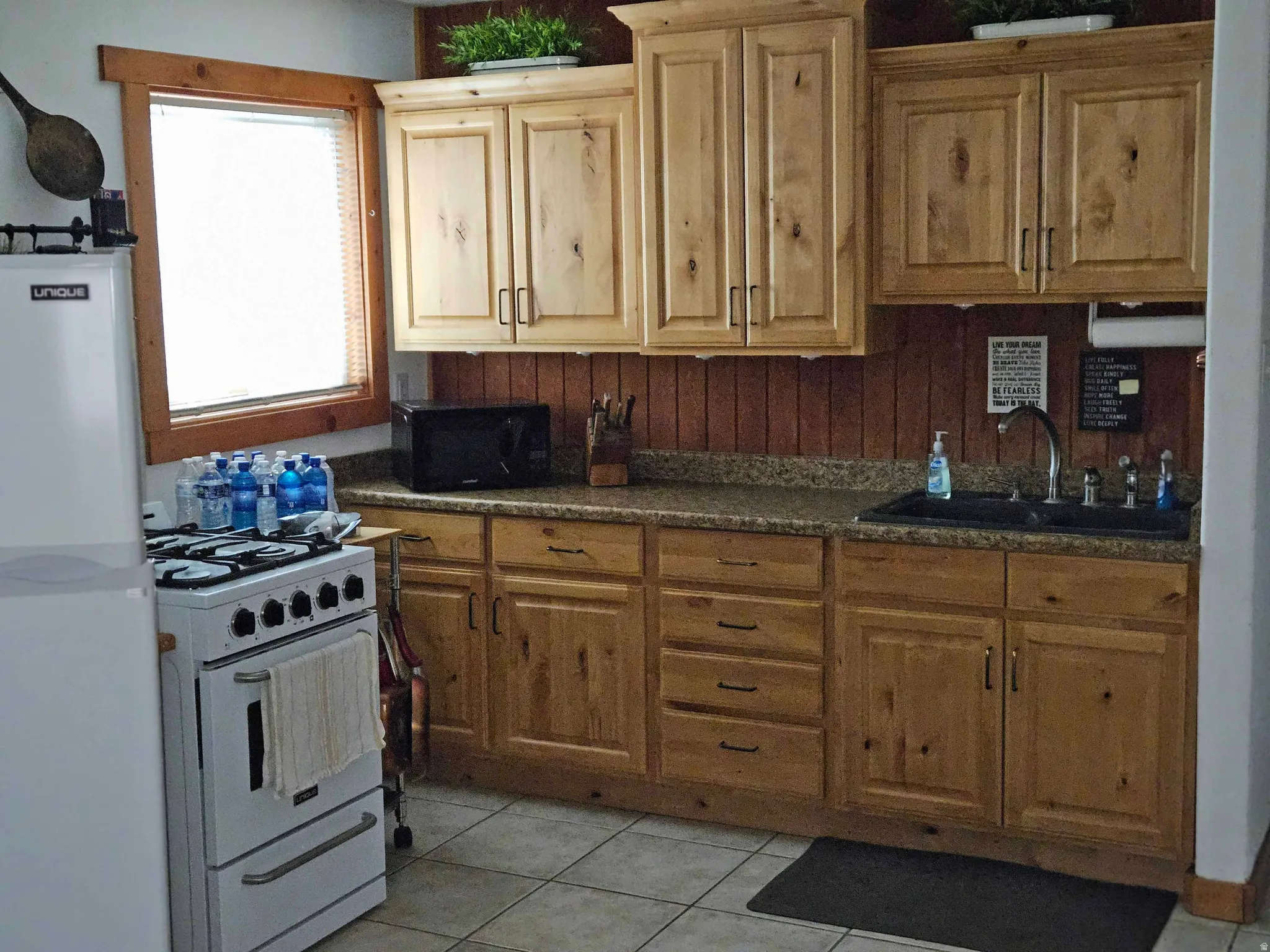Kitchen featuring dark countertops, white appliances, and light tile patterned floors