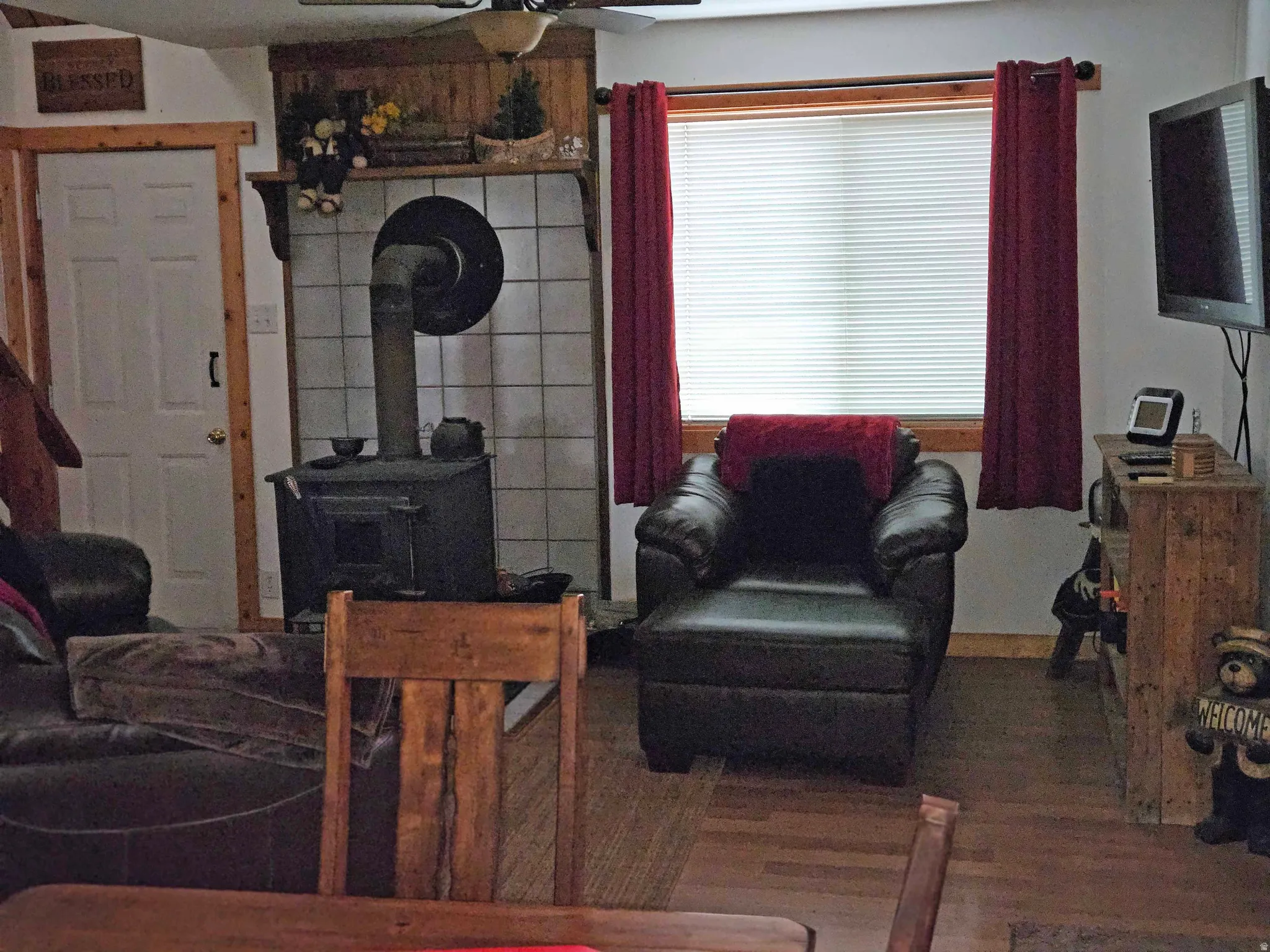 Living room with a wood stove, ceiling fan, and wood finished floors