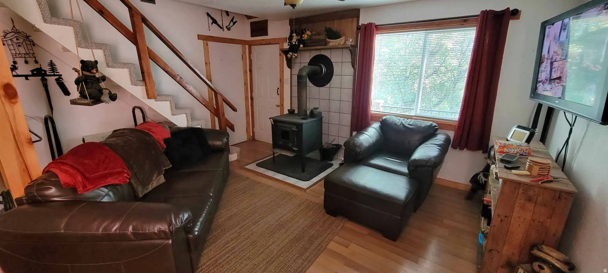 Living room featuring a wood stove, stairway, and wood finished floors