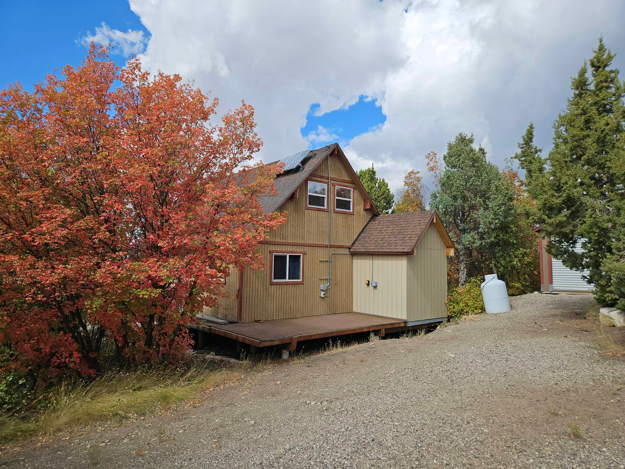 Rear view of house with a wooden deck, roof mounted solar panels, and roof with shingles