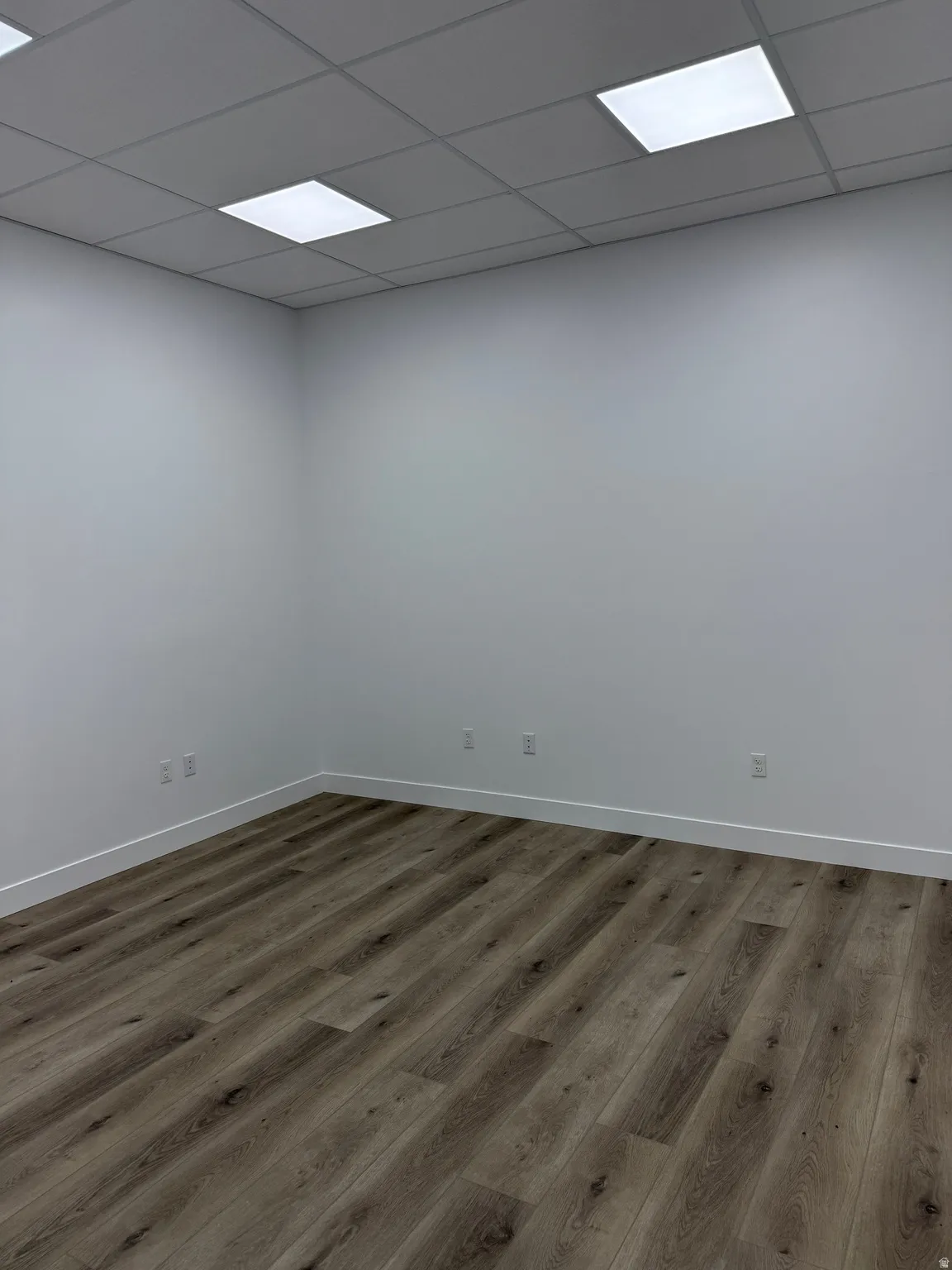 Empty room with wood finished floors and a drop ceiling