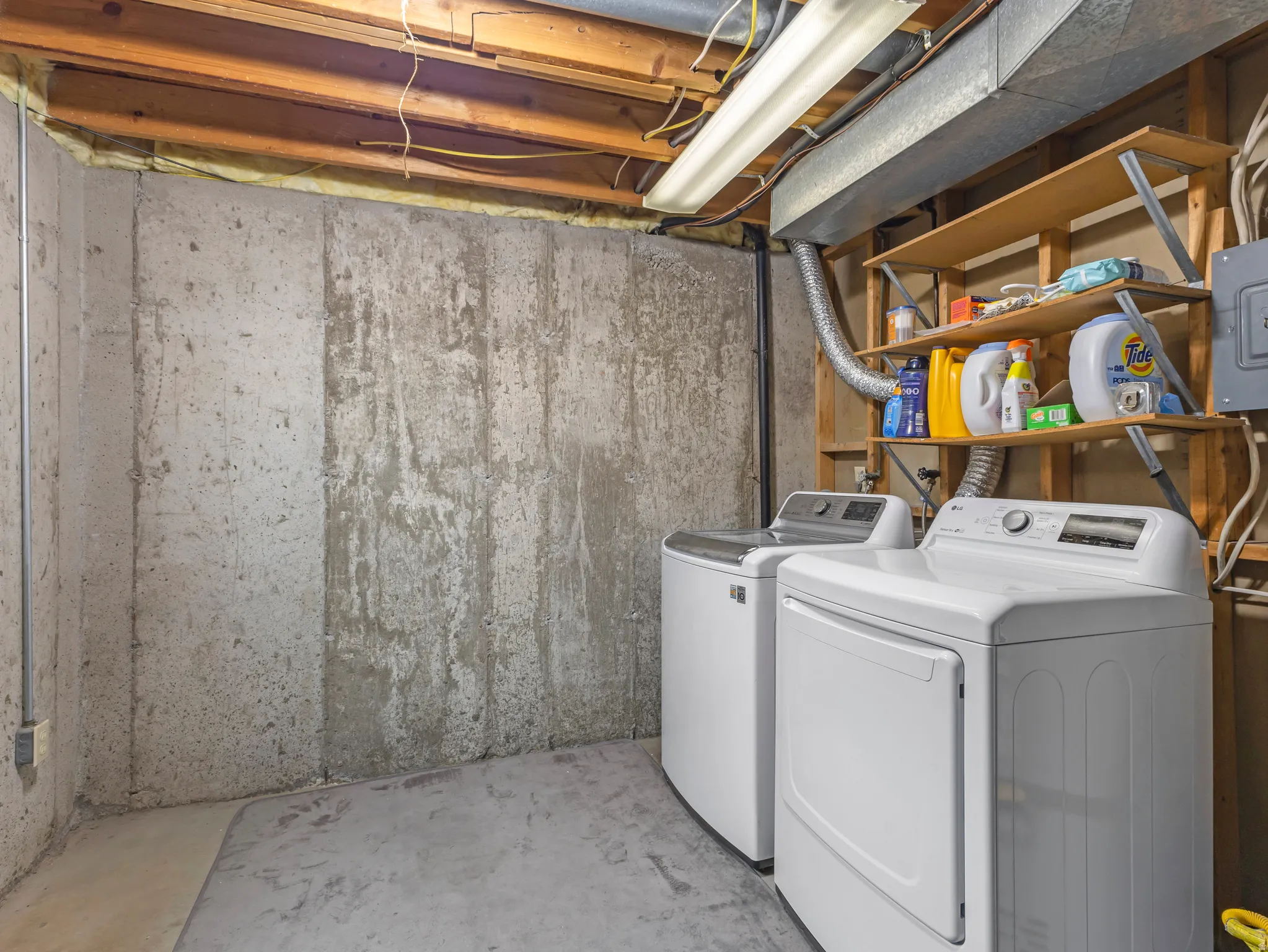 Laundry area featuring unfinished concrete flooring, independent washer and dryer, and electric panel