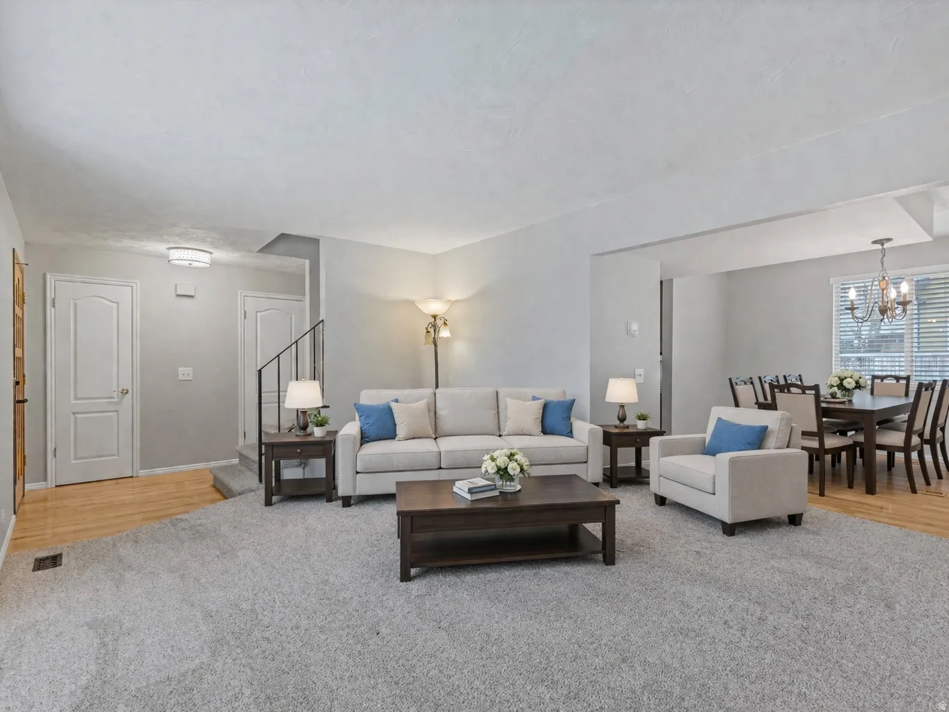 Living area featuring suspended lighting and light colored carpet