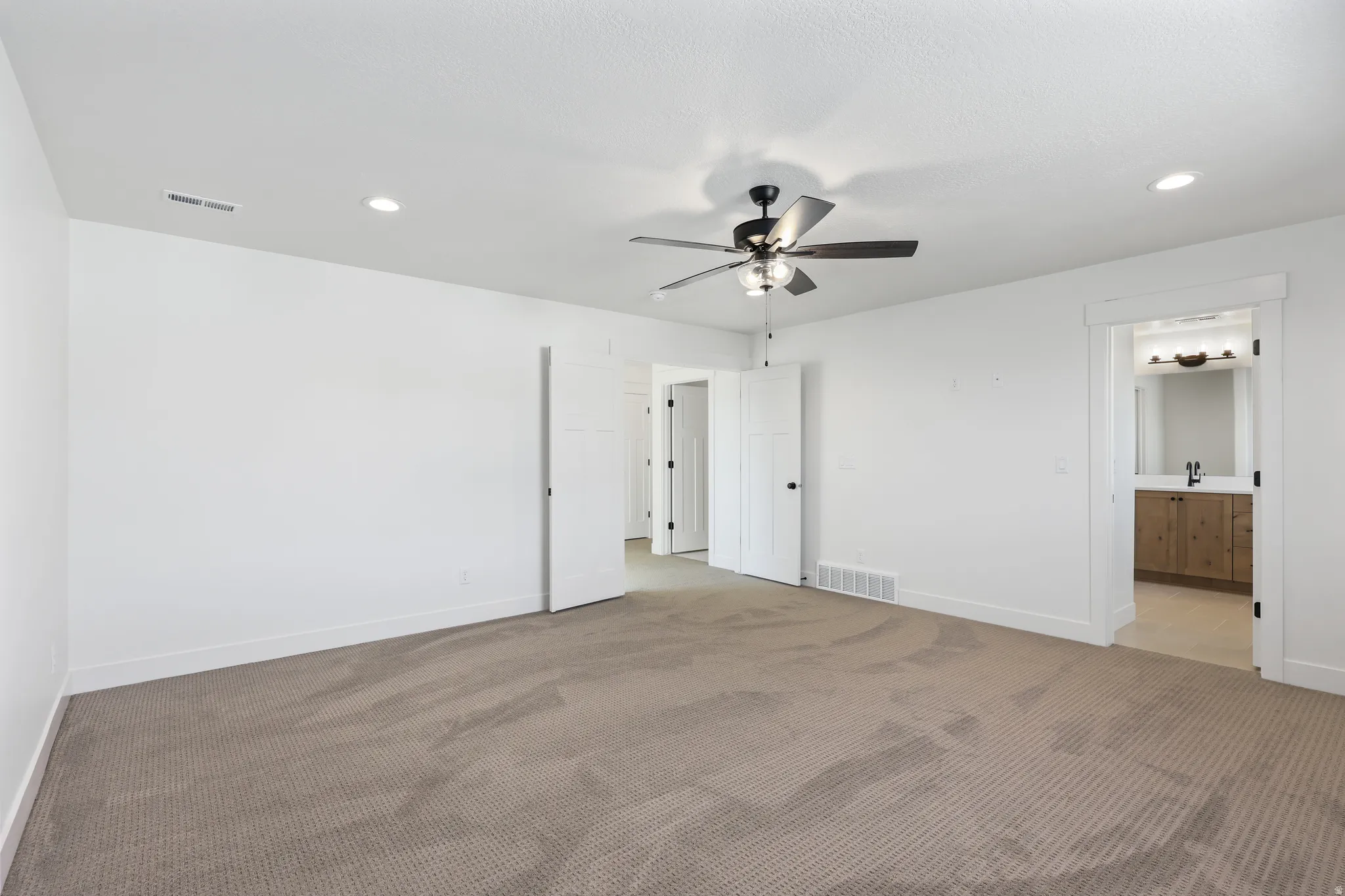 Unfurnished bedroom with recessed lighting, carpet flooring, a ceiling fan, and ensuite bath