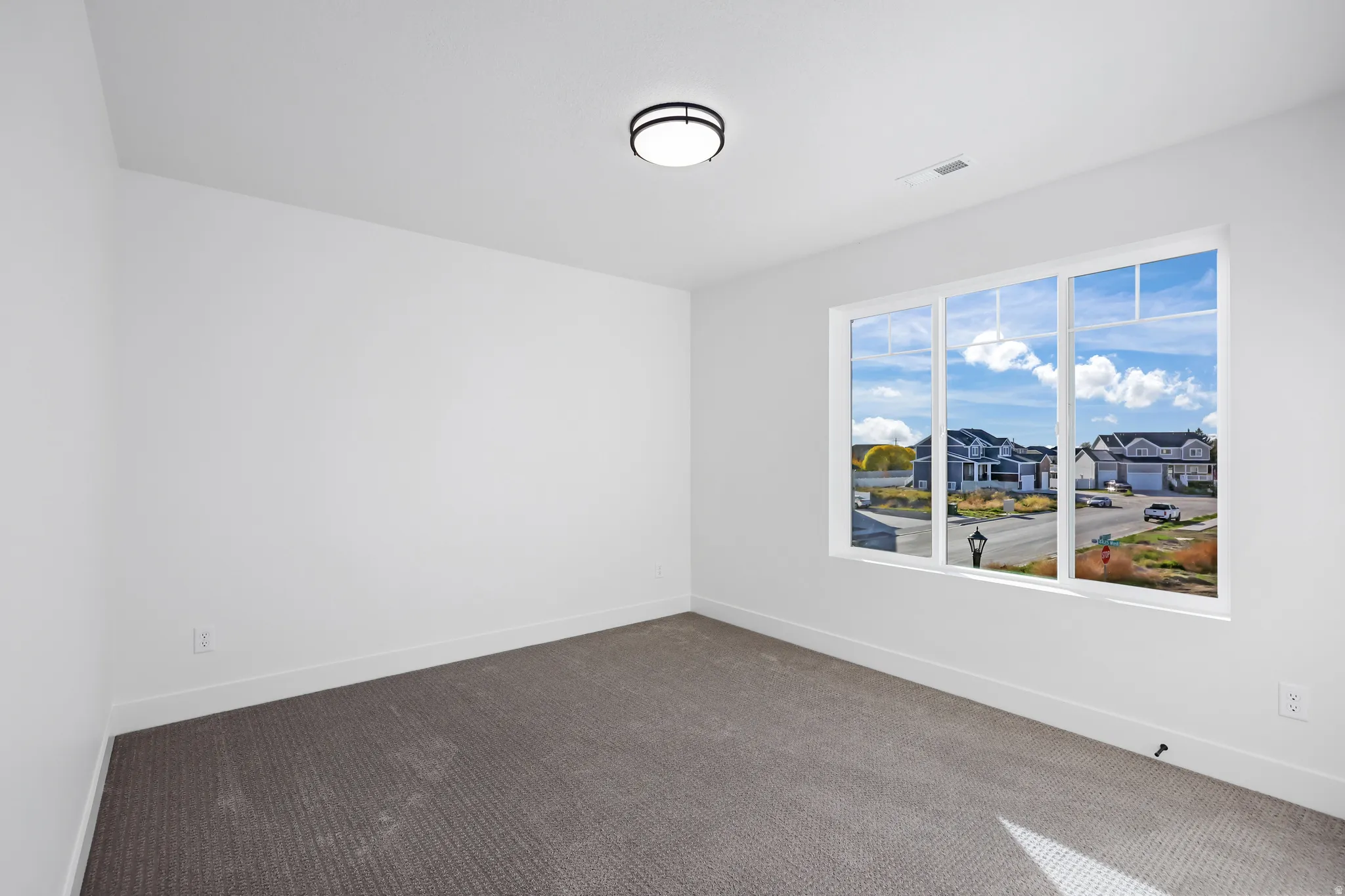 Carpeted empty room with baseboards and a residential view