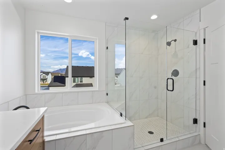Bathroom featuring vanity, a garden tub, a marble finish shower, and recessed lighting