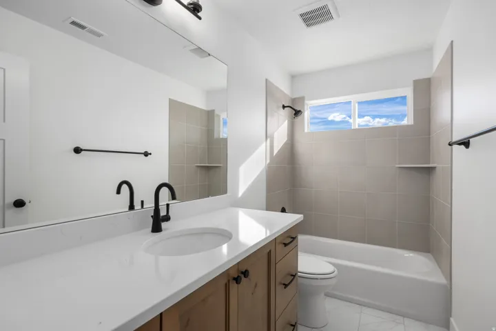 Bathroom featuring vanity, shower / tub combination, and light marble finish flooring