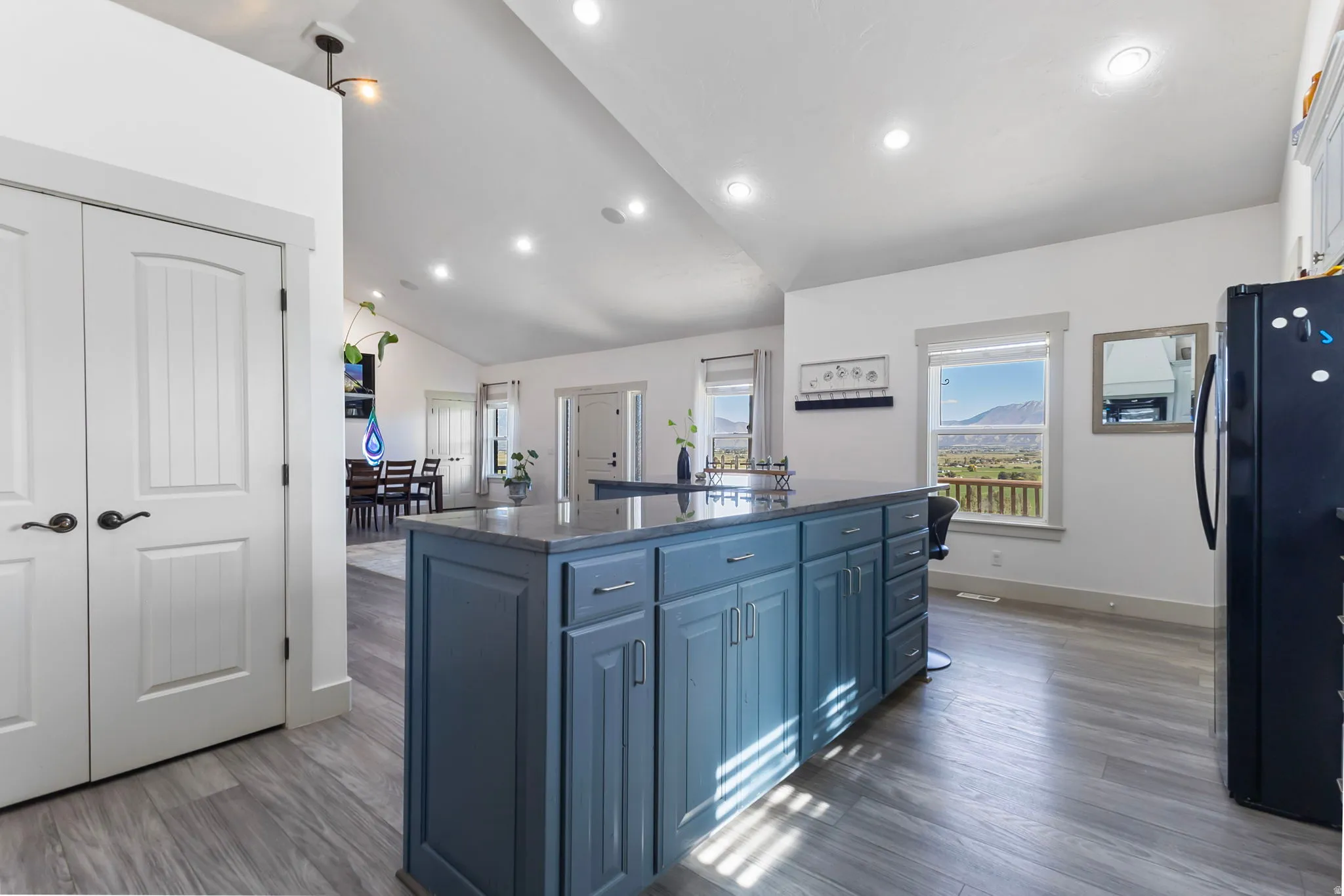Kitchen featuring a large island with quartzite countertops and a breakfast bar, tasteful backsplash, and high vaulted ceiling