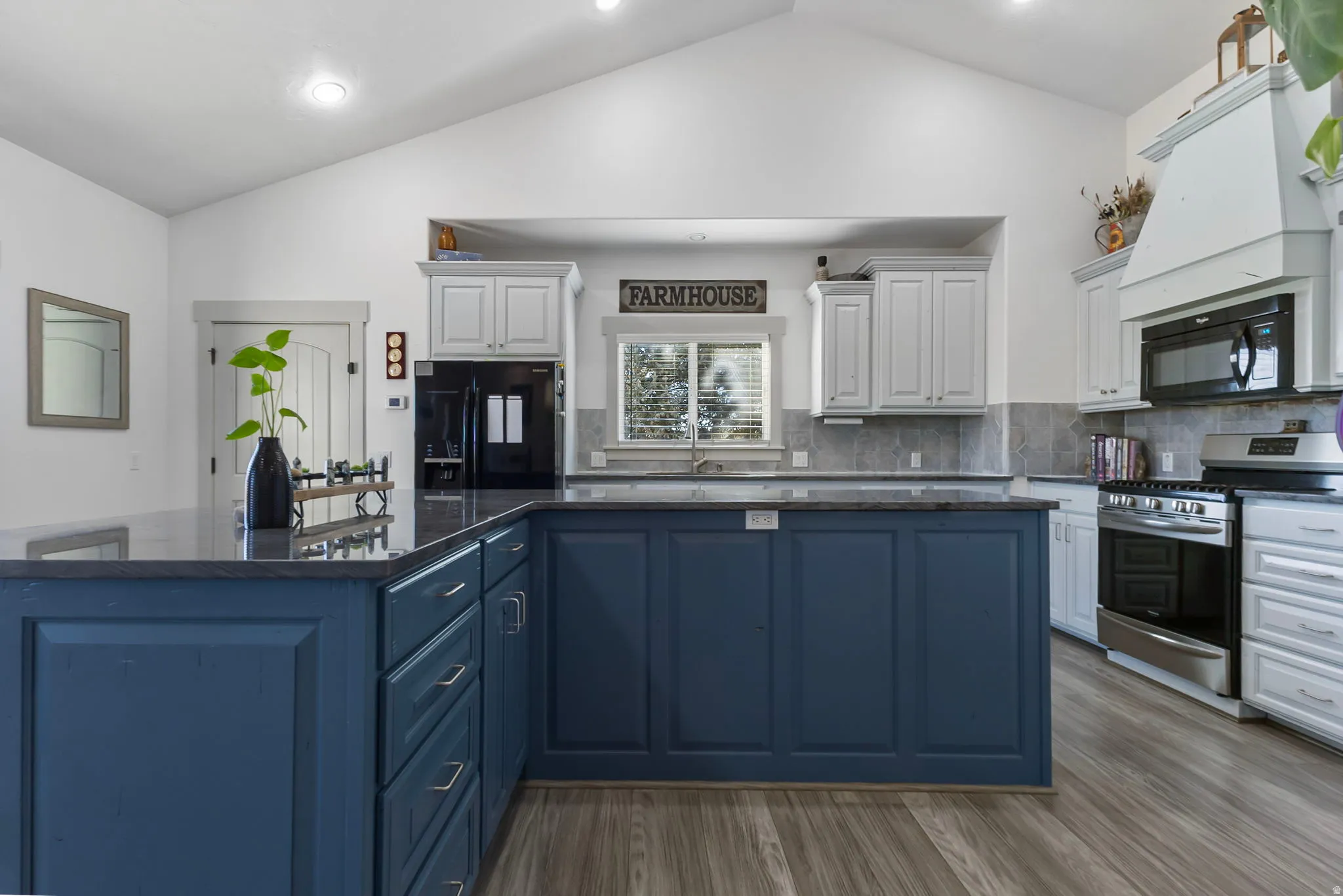 Kitchen featuring a large island with quartzite countertops and a breakfast bar, tasteful backsplash, and high vaulted ceiling