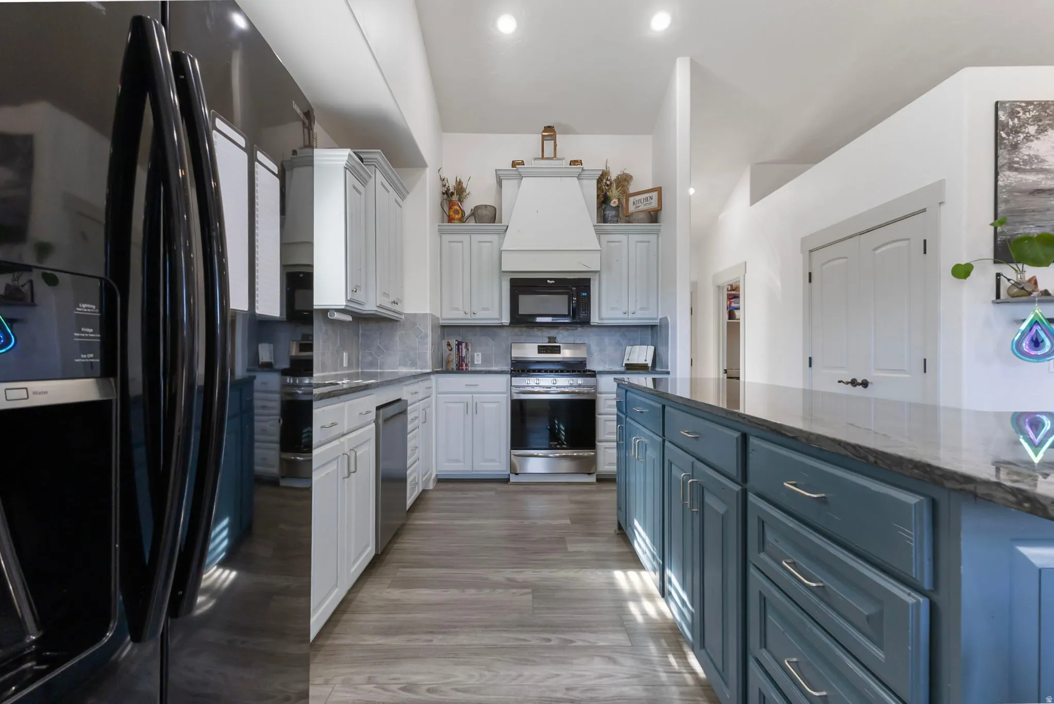 Kitchen featuring a large island with quartzite countertops and a breakfast bar, tasteful backsplash, and high vaulted ceiling