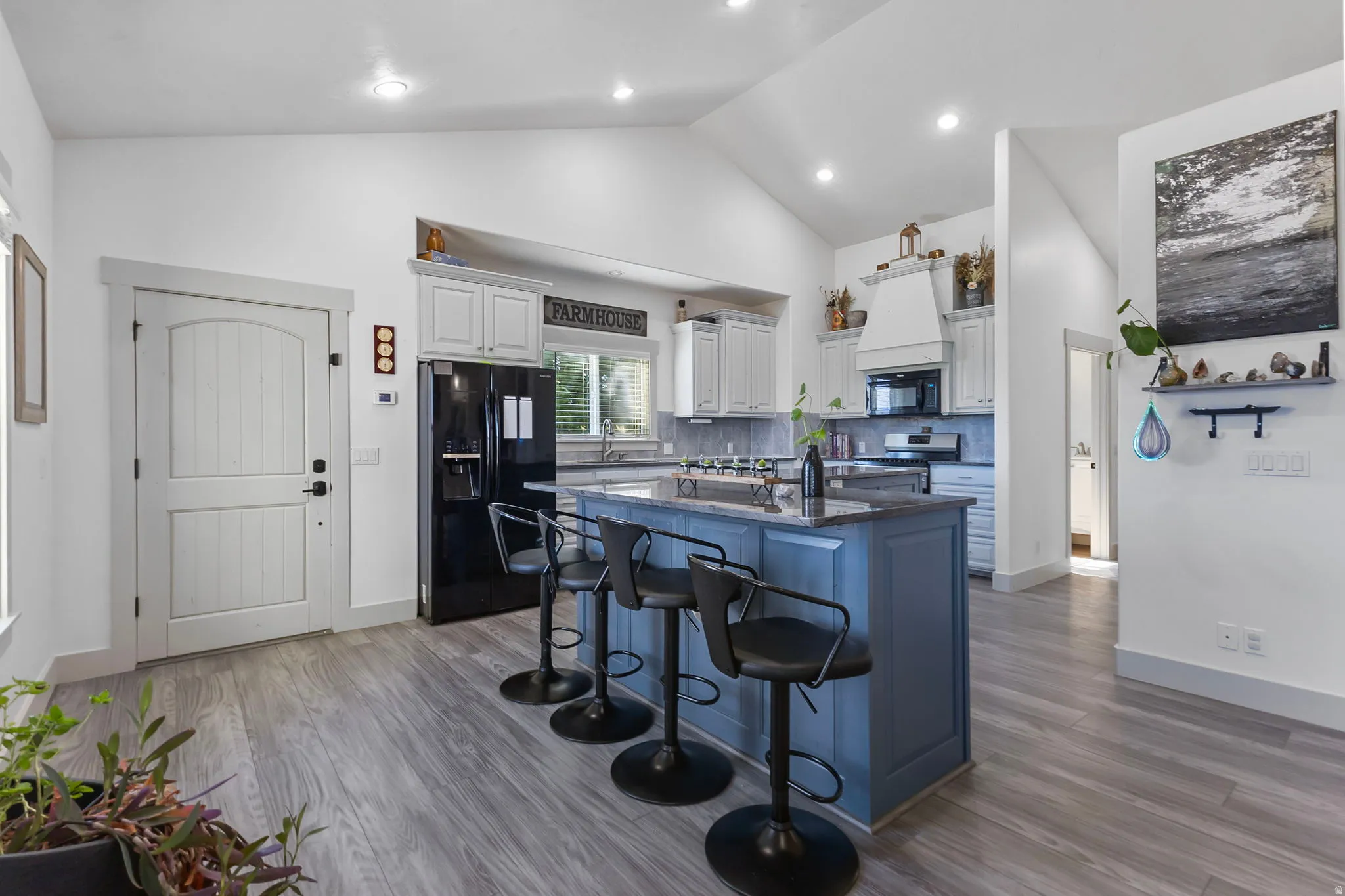Kitchen featuring a large island with quartzite countertops and a breakfast bar, tasteful backsplash, and high vaulted ceiling