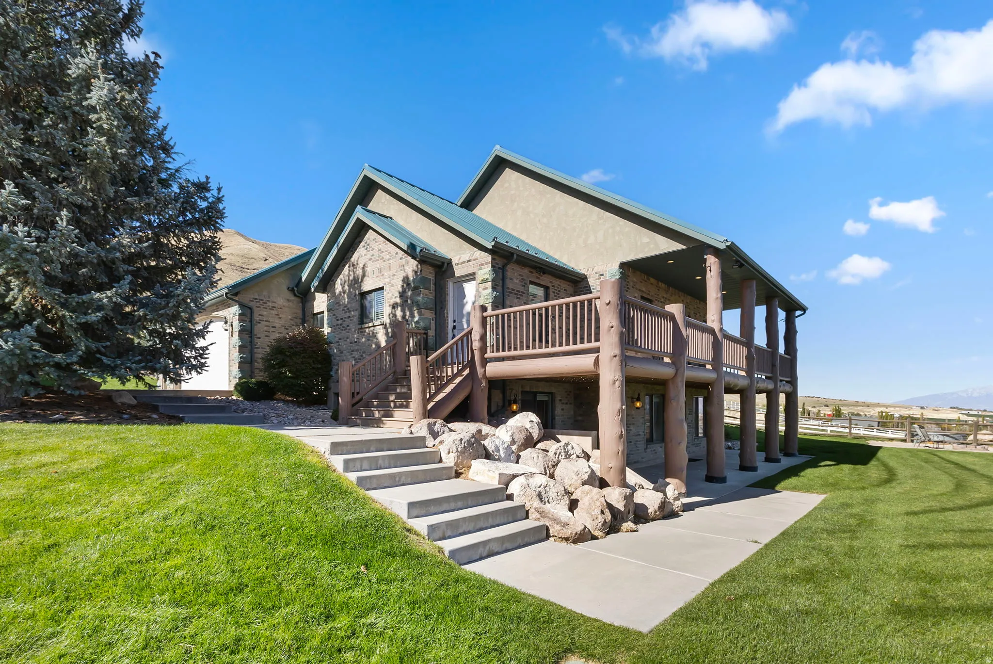 Front door and stairs leading to the basement patio and walkout entrance, beautifully kept grass, mature trees, and enchanting views.