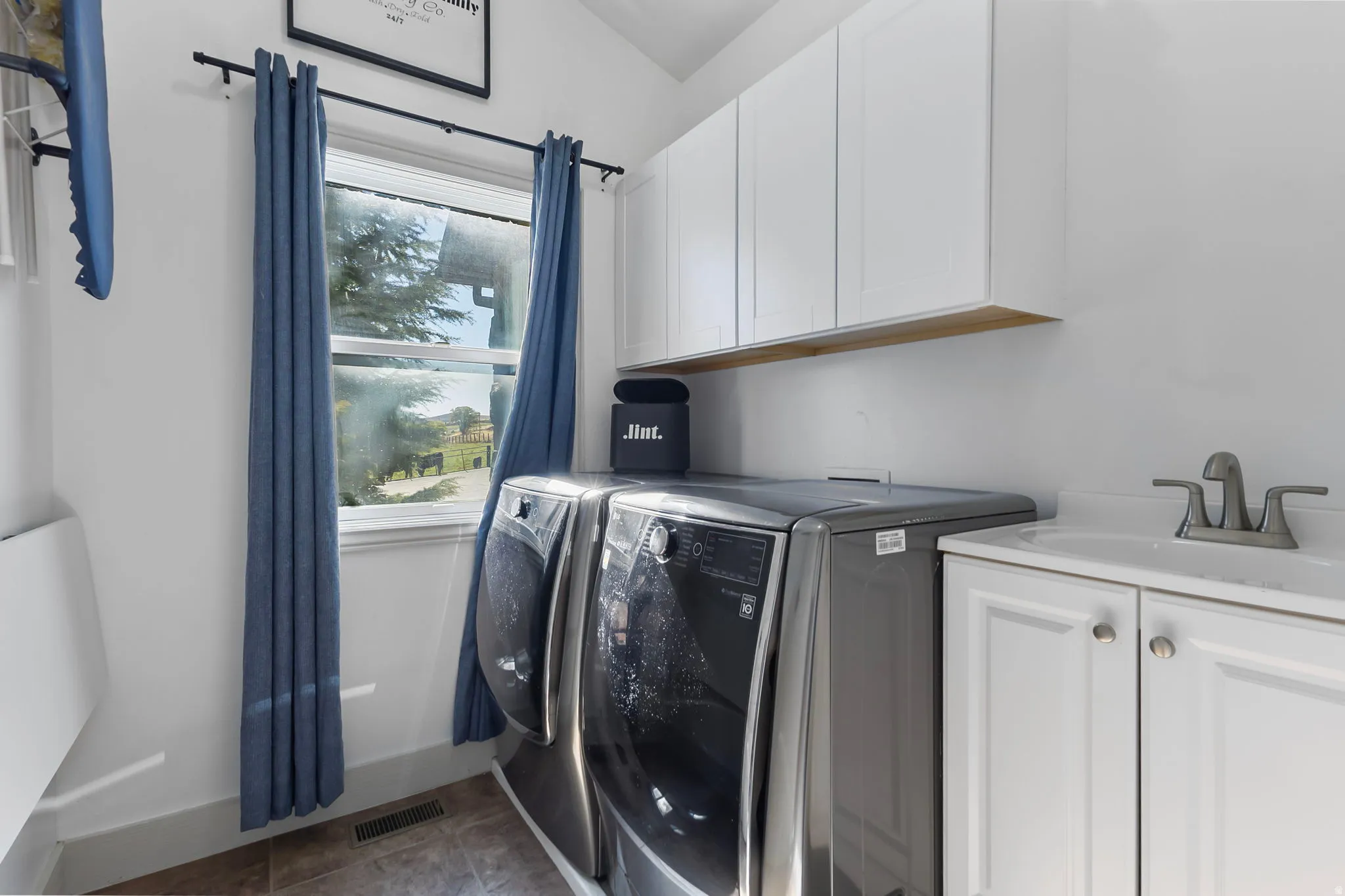 Laundry room with washer and clothes dryer, cabinet space, and tile floors
