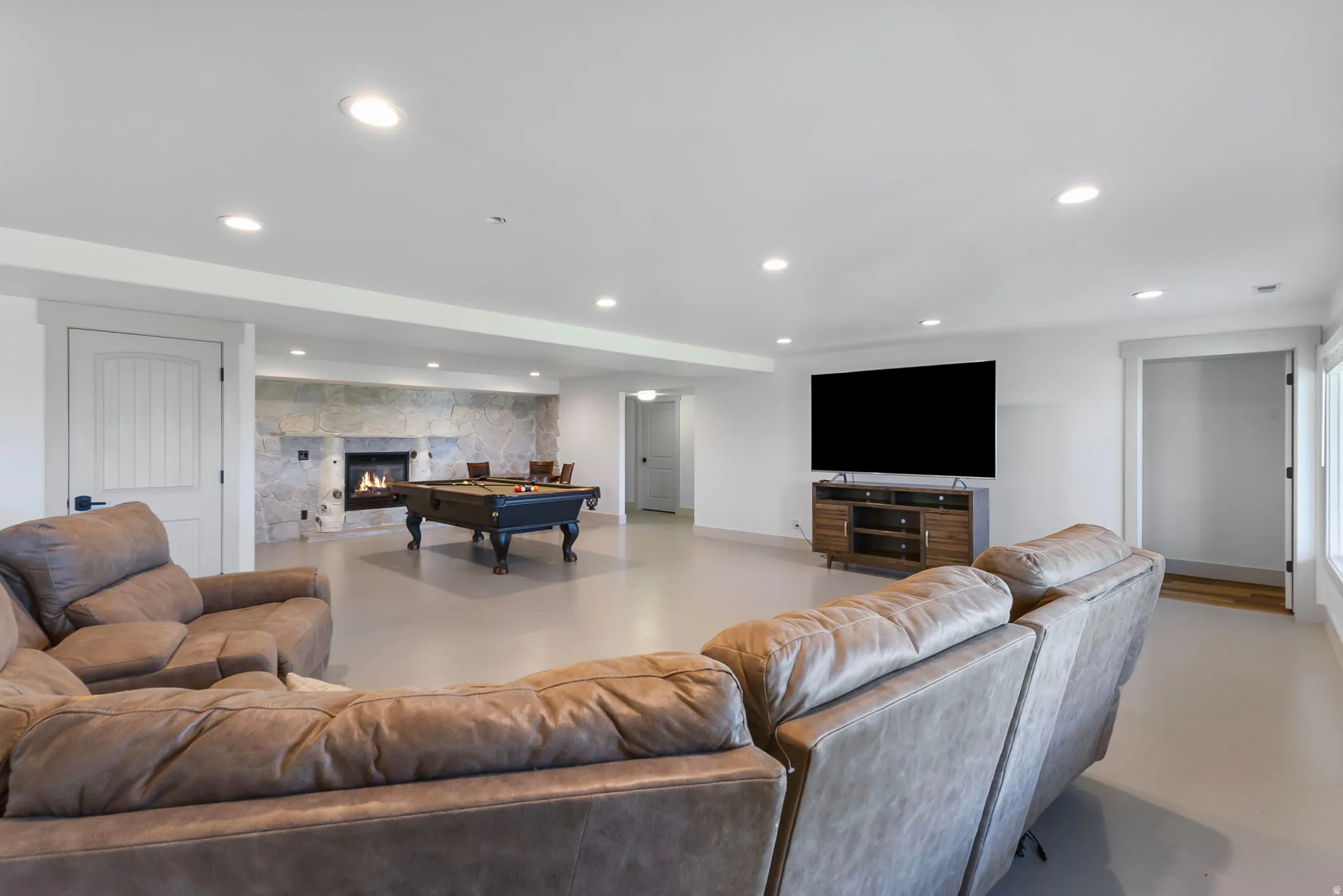 Recreation room with billiards table, recessed lighting and a stone fireplace