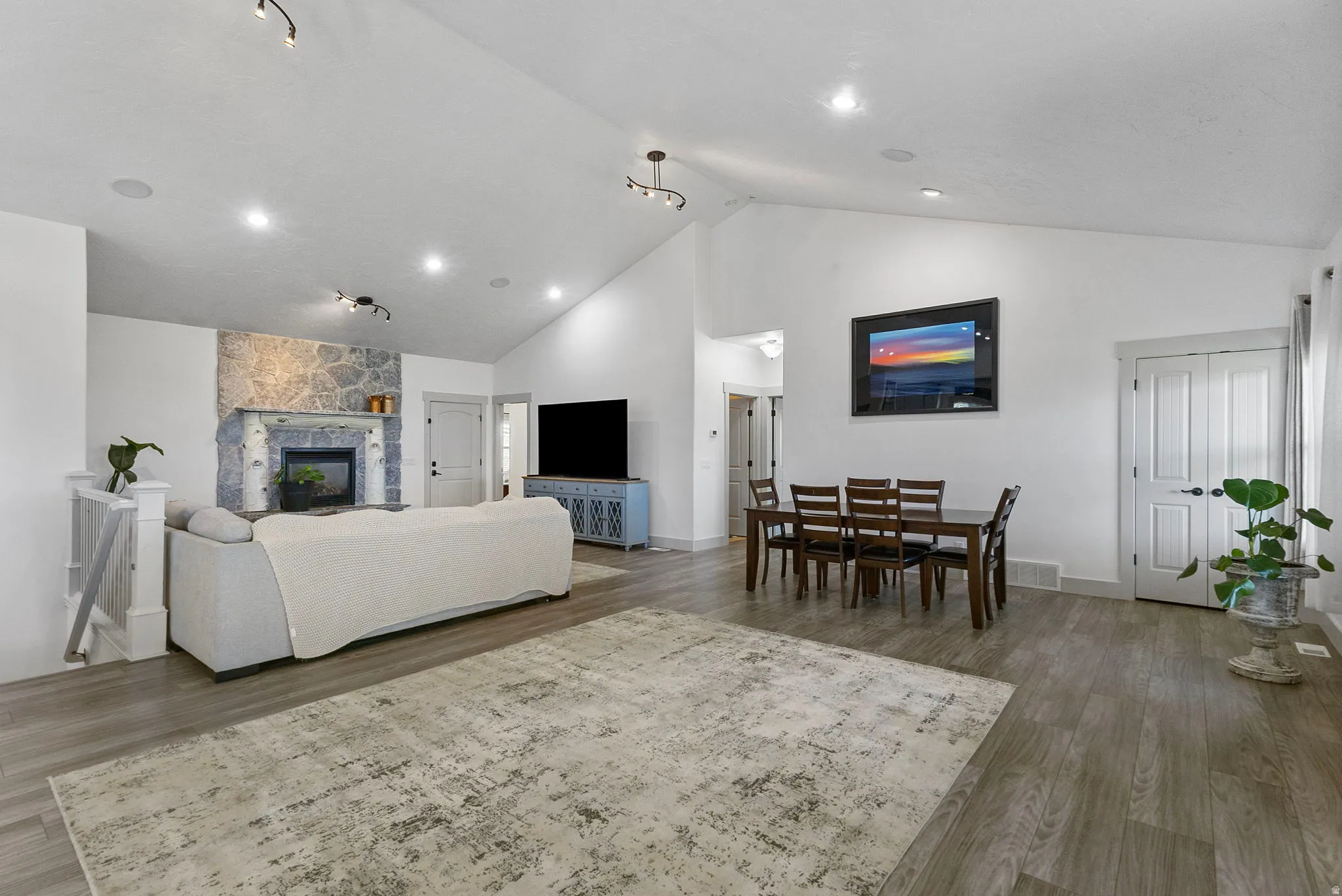 Living area with high vaulted ceiling, a stone fireplace, and recessed lighting