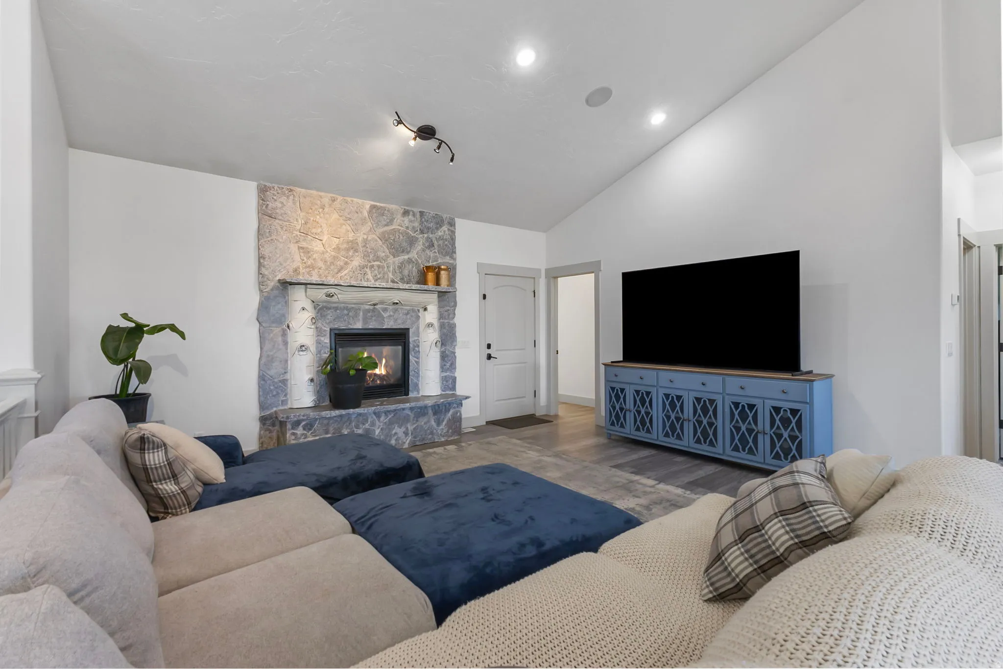 Living room featuring a stone fireplace, high vaulted ceiling, and recessed lighting