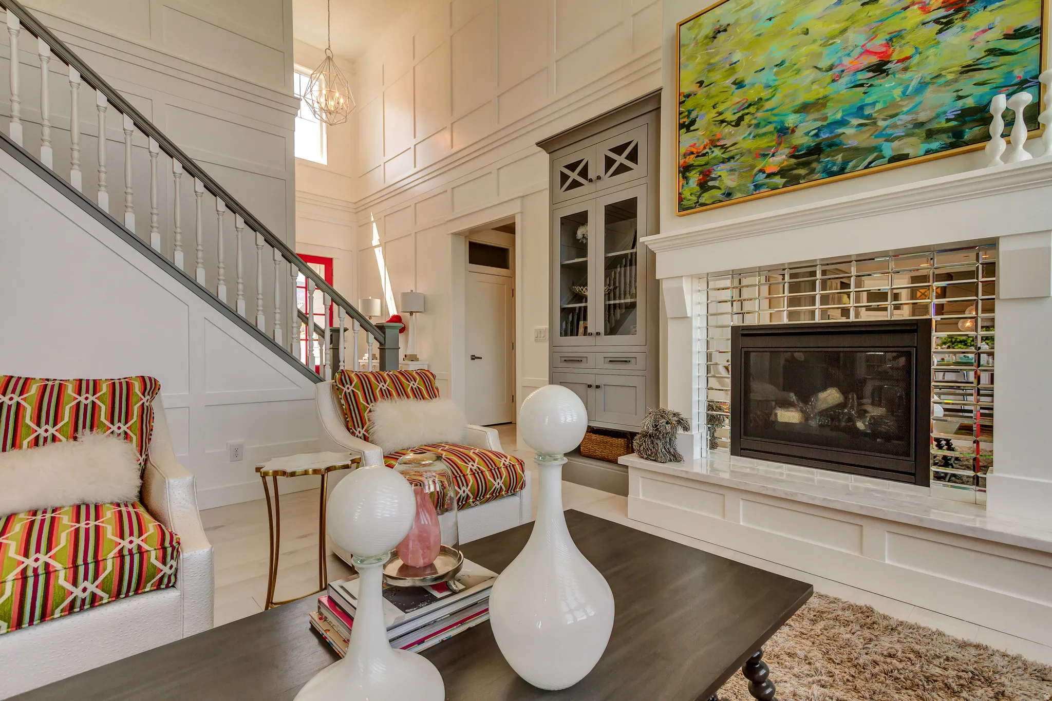 Living area featuring a decorative wall, a tiled fireplace, a high ceiling, stairway, and wood finished floors