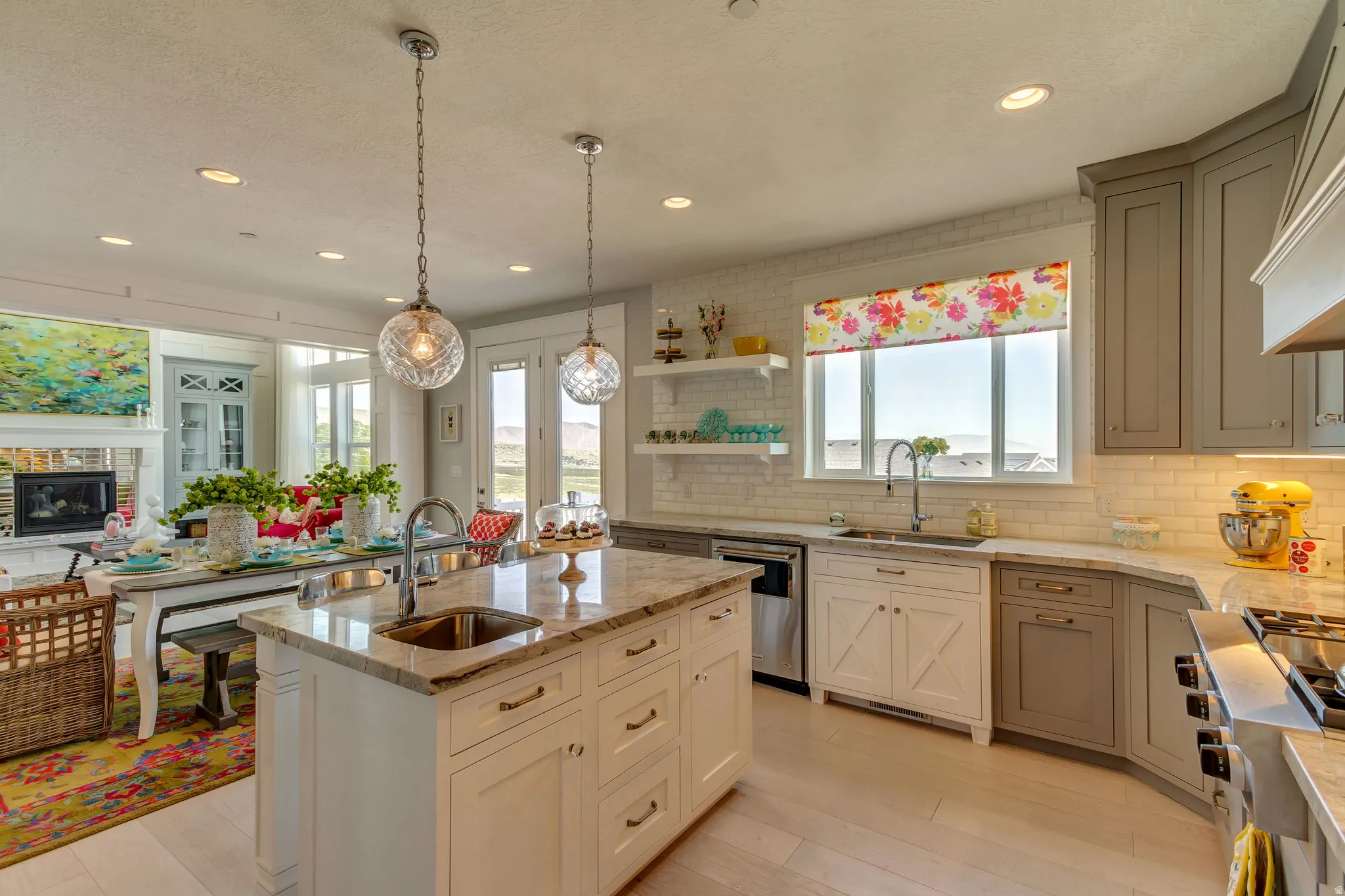 Kitchen with light stone counters, hanging light fixtures, a glass covered fireplace, stainless steel appliances, and open shelves