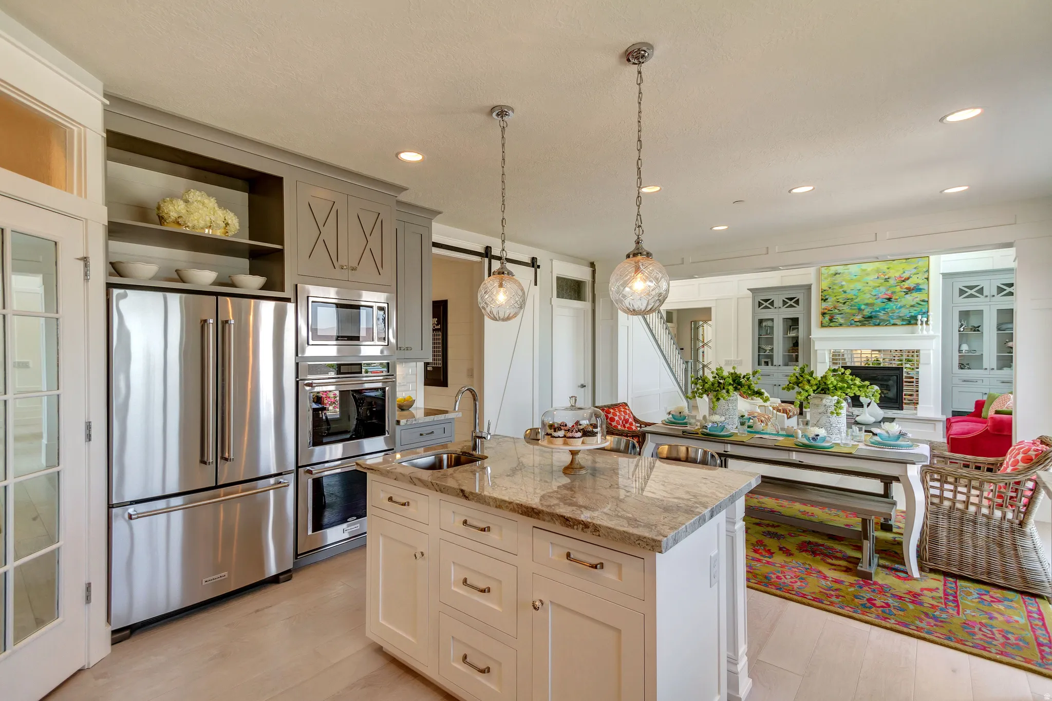 Kitchen featuring appliances with stainless steel finishes, light stone countertops, open shelves, pendant lighting, and a barn door
