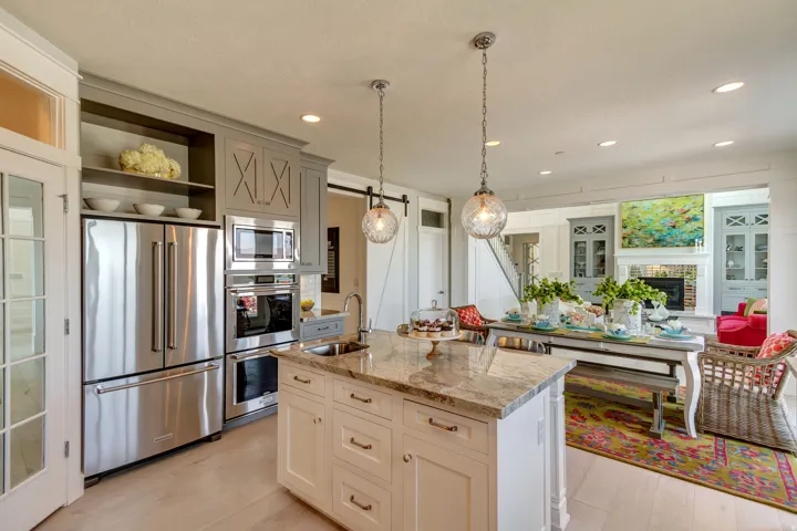 Kitchen featuring appliances with stainless steel finishes, light stone countertops, open shelves, pendant lighting, and a barn door