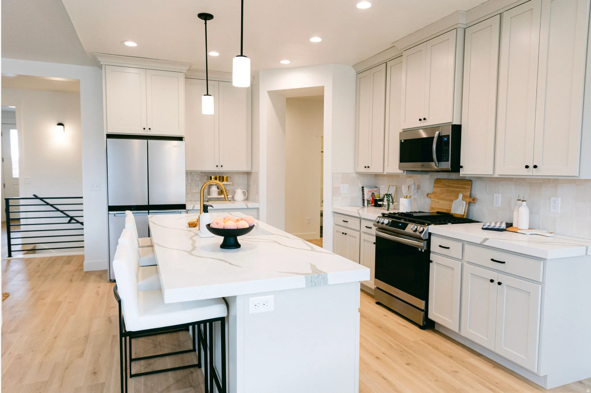 Kitchen with stainless steel appliances, a center island with sink, a kitchen breakfast bar, and light wood-style floors