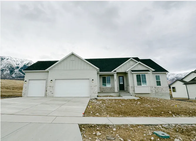 View of front facade featuring board and batten siding, an attached garage, a mountain view, driveway, and stone siding