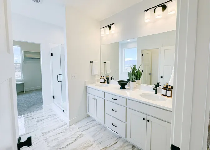 Bathroom featuring double vanity, a shower stall, light marble finish floors, and a walk in closet