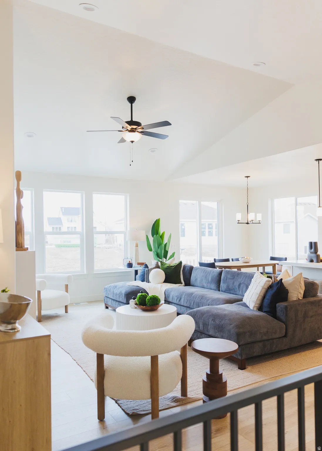 Living room featuring vaulted ceiling, light wood-style flooring, a ceiling fan, and a chandelier