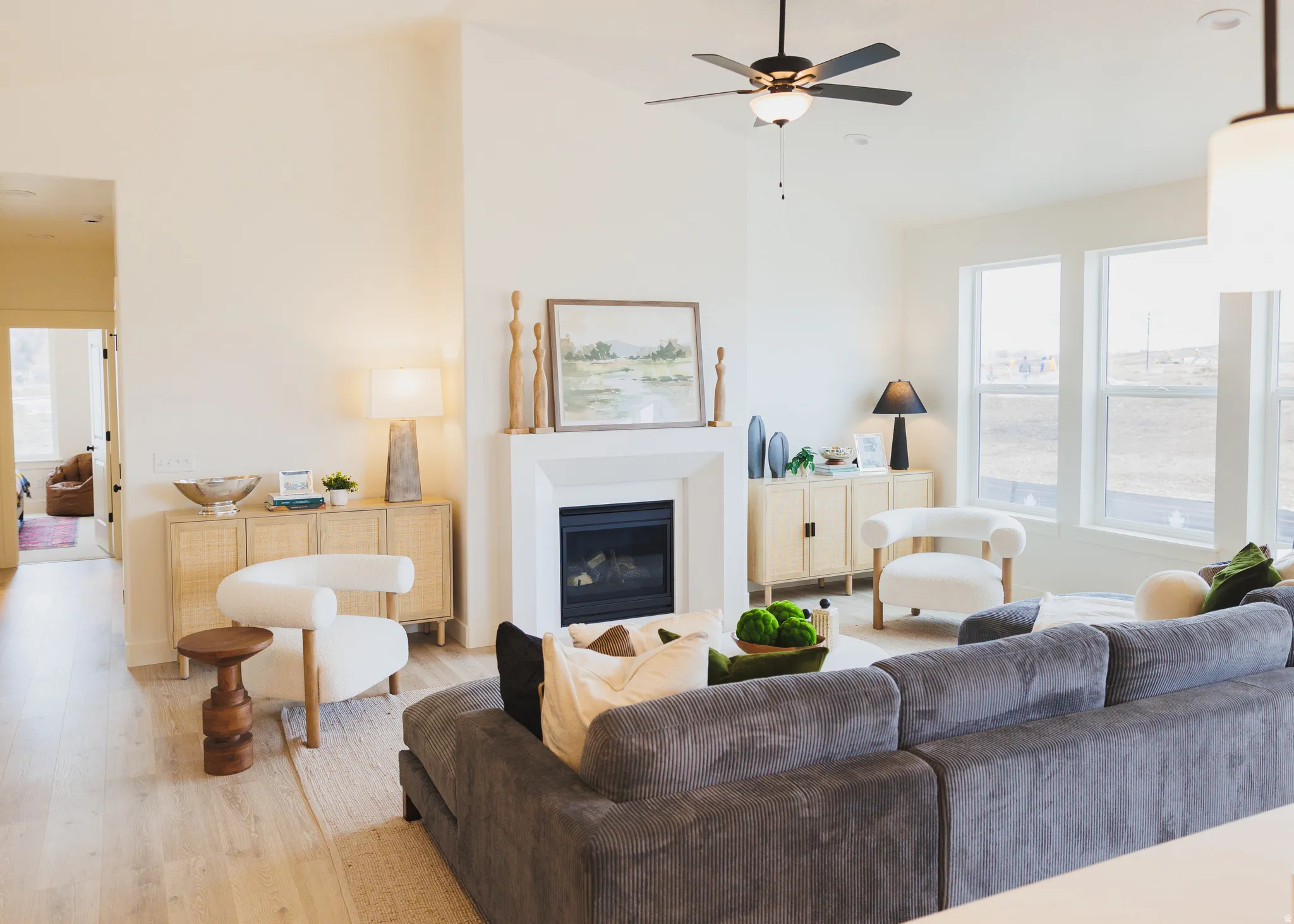 Living room featuring wood finished floors, a glass covered fireplace, ceiling fan, and lofted ceiling