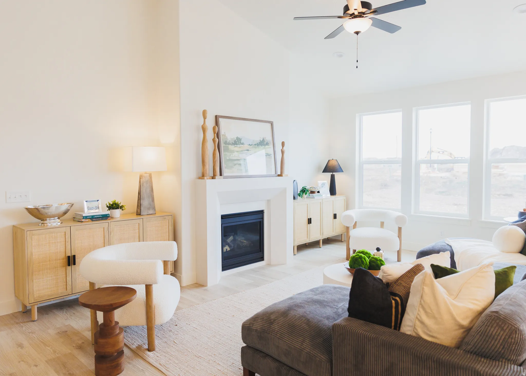Living area with a glass covered fireplace, wood finished floors, lofted ceiling, and a ceiling fan