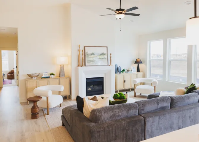 Living room featuring wood finished floors, a glass covered fireplace, ceiling fan, and lofted ceiling