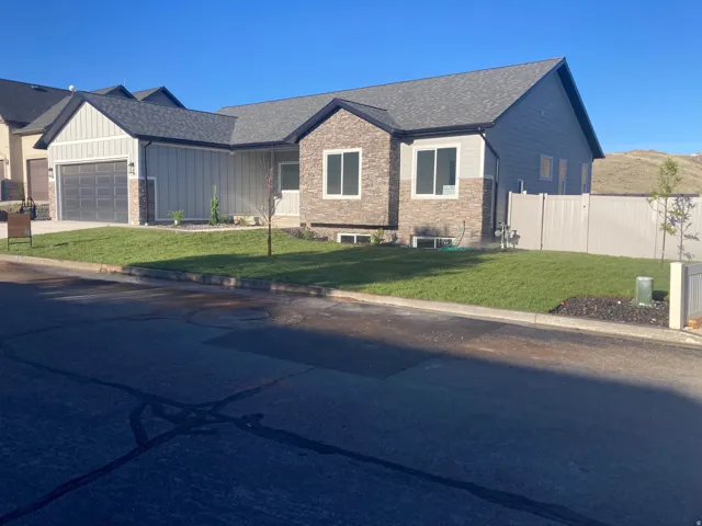 View of front of house with an attached garage, a shingled roof, board and batten siding, stone siding, and driveway