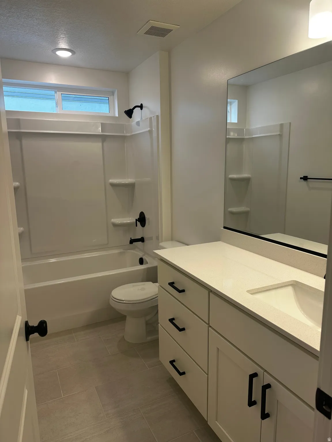 Bathroom with vanity, tub / shower combination, and a textured ceiling