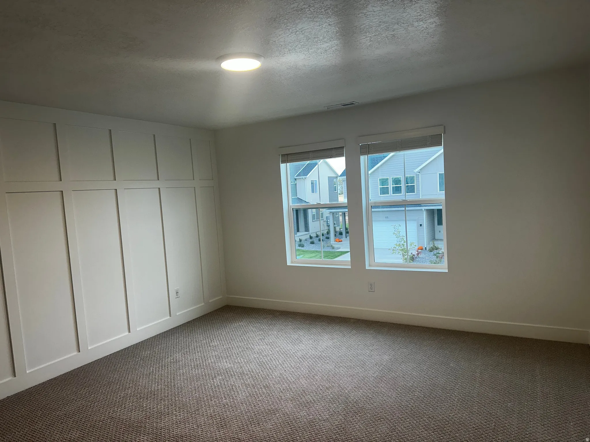 Carpeted empty room featuring a textured ceiling and baseboards