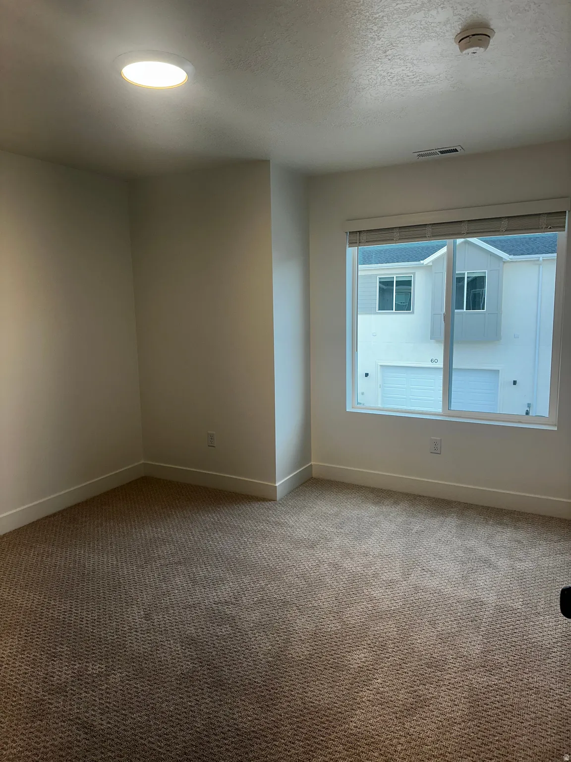 Carpeted empty room with a textured ceiling, a smoke detector, and recessed lighting