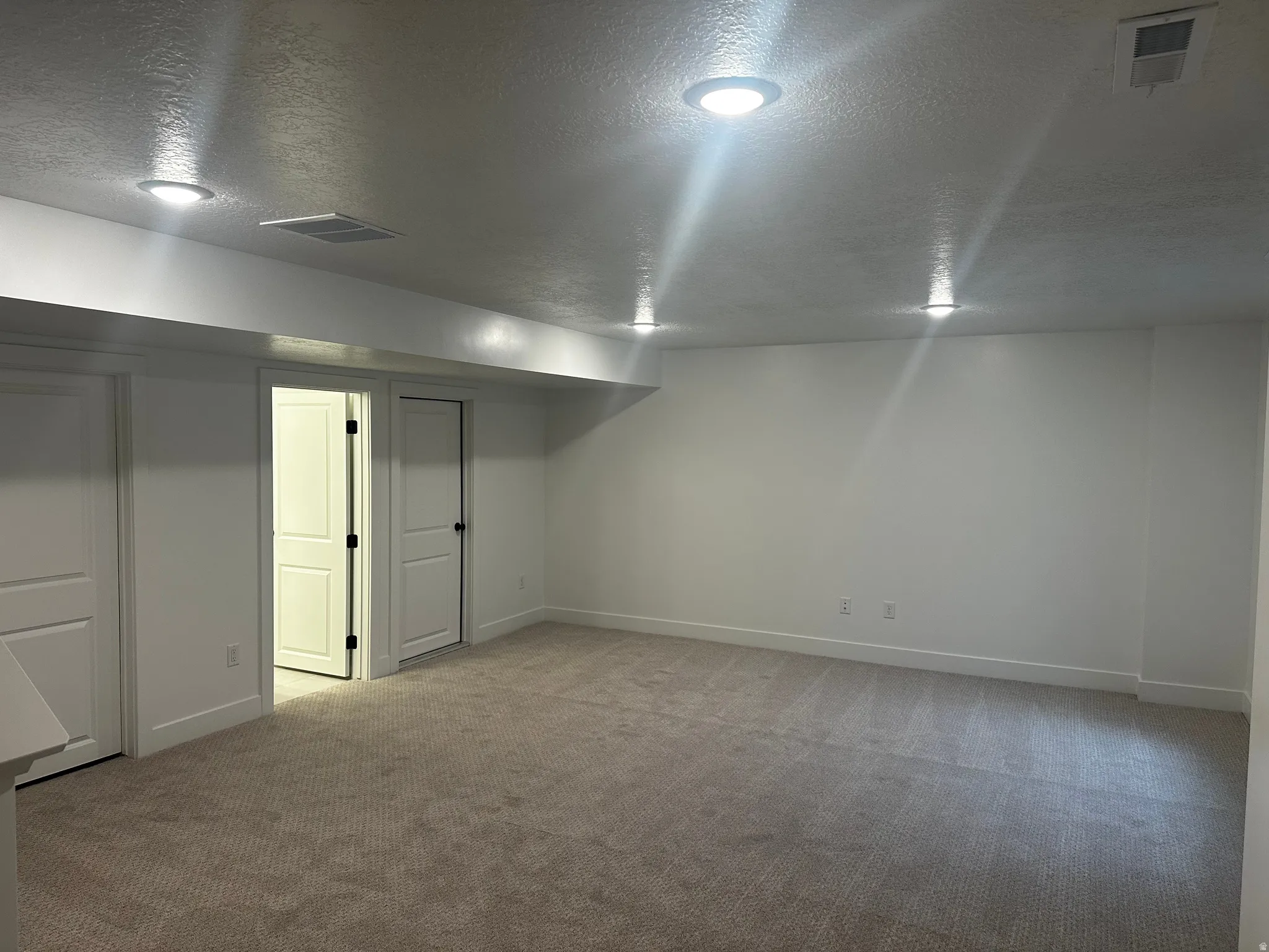 Finished below grade area featuring a textured ceiling and light colored carpet