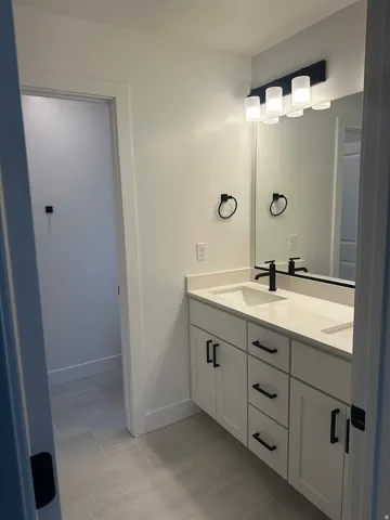 Bathroom with double vanity, a textured ceiling, and light tile patterned flooring
