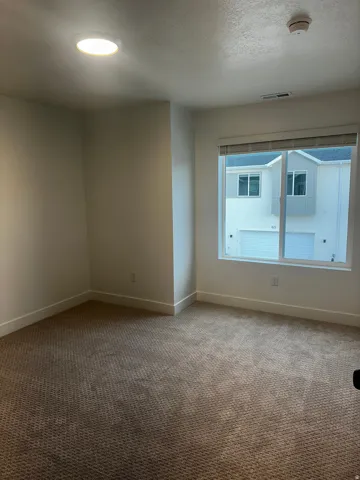 Carpeted empty room with a textured ceiling, a smoke detector, and recessed lighting