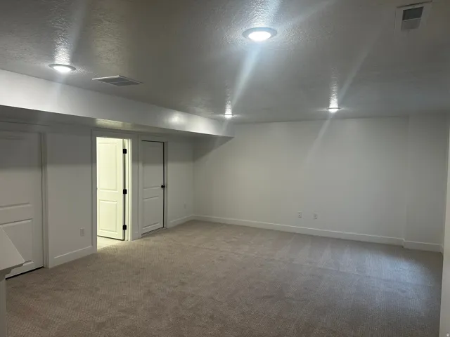 Finished below grade area featuring a textured ceiling and light colored carpet